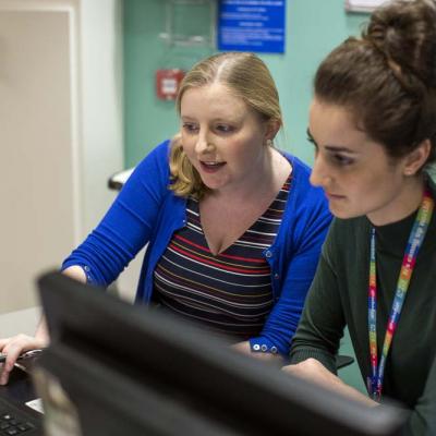 Two doctors check information together on a computer screen