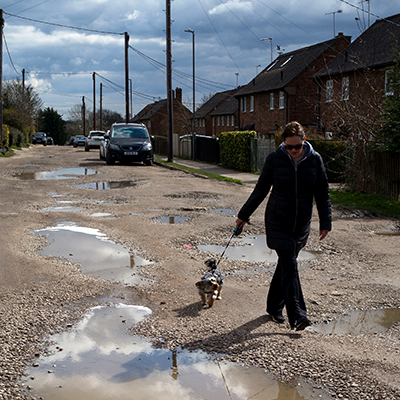 Woman walking dog on road with puddle