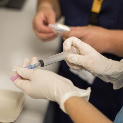 Gloved hands preparing a syringe
