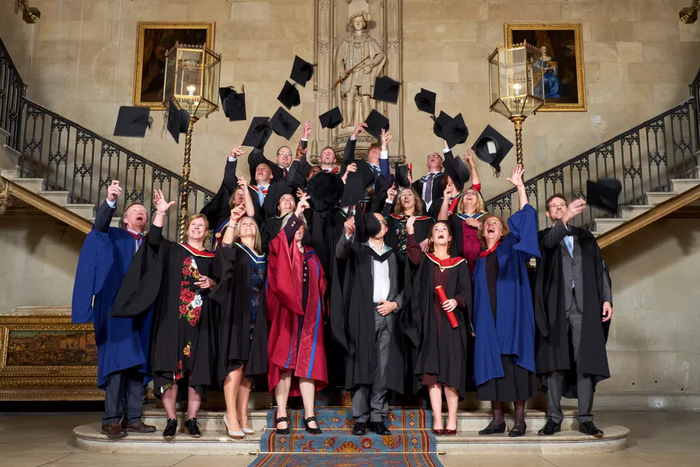 New members of GenerationQ fellowship celebrate their graduation by throwing their mortar board hats up into the air