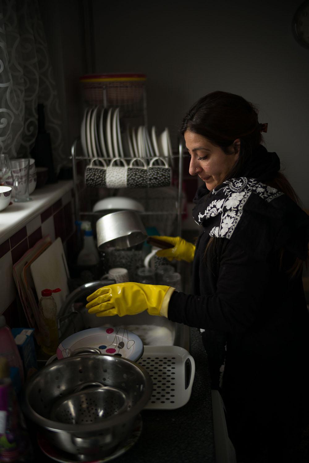 A lady wearing yellow washing up gloves washing pots and pans