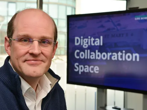 Erik Mayer headshot in front of a screen that reads Digital Collaboration Space