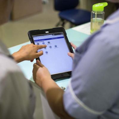 Two nurses looking at data on an iPad screen