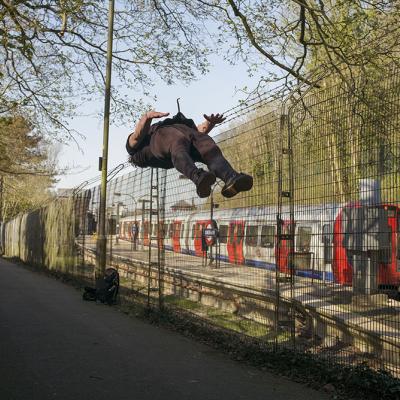 A man doing a backflip next to a tube line