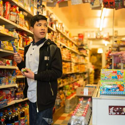 A boy in a sweet shop holding a chocolate bar