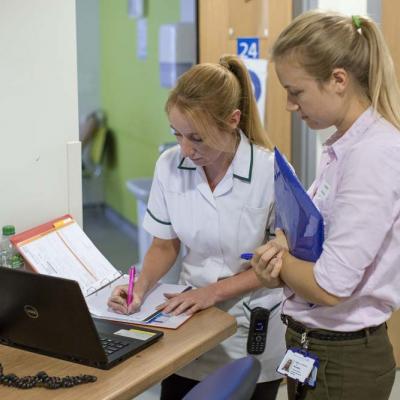 Two NHS workers entering data into computer system