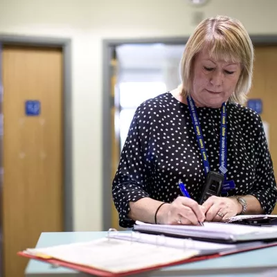 Worker writing in a book in a corridor