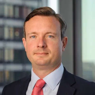 Headshot of Alex Schoenfeldt, a white man in a suit and red tie