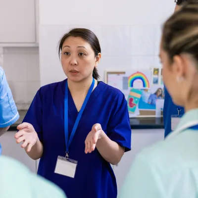 A small group of medical and health care professionals stand for a meeting in a communal staffroom in Newcastle upon Tyne, North East England