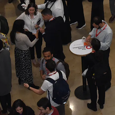 A group of delegates seen from above networking at a Health Foundation event with Health Foundation branded tables visible.